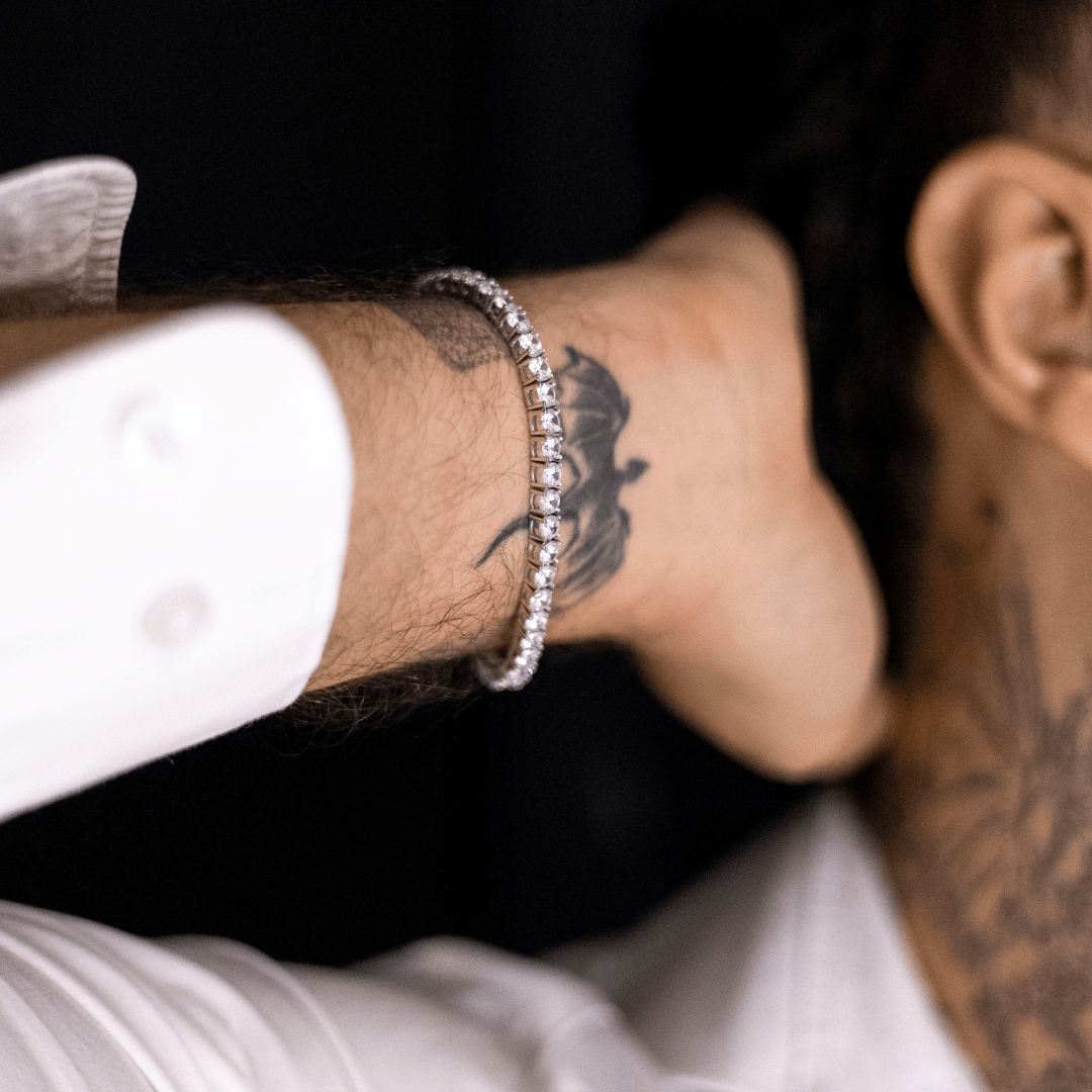 close-up-de-pulseira-riviera-prata-no-pulso-masculino-com-camisa-branca-e-tatuagem-no-pescoco