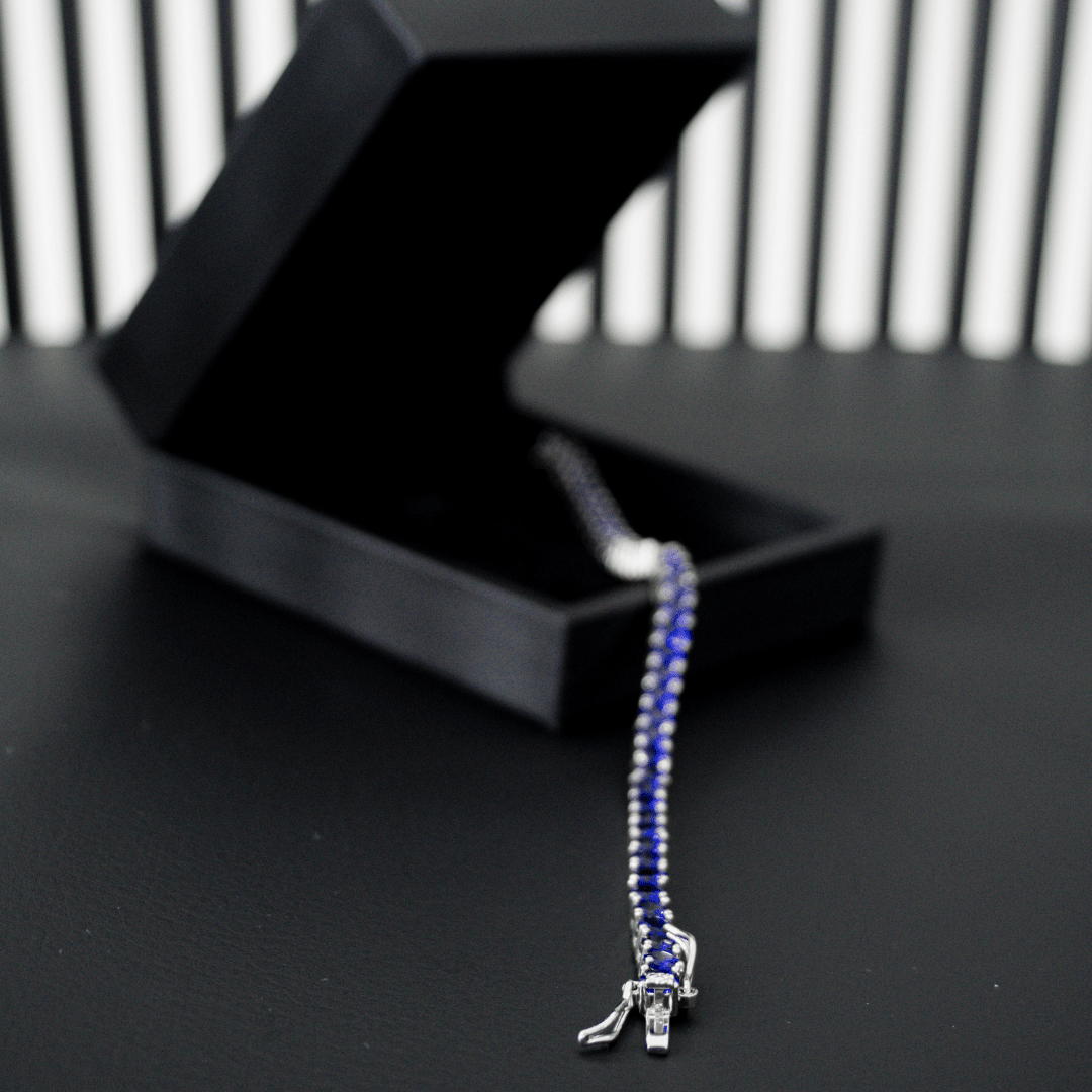 pulseira-riviera-com-zirconias-azuis-sobre-caixa-de-luxo-preta-com-fundo-listrado
